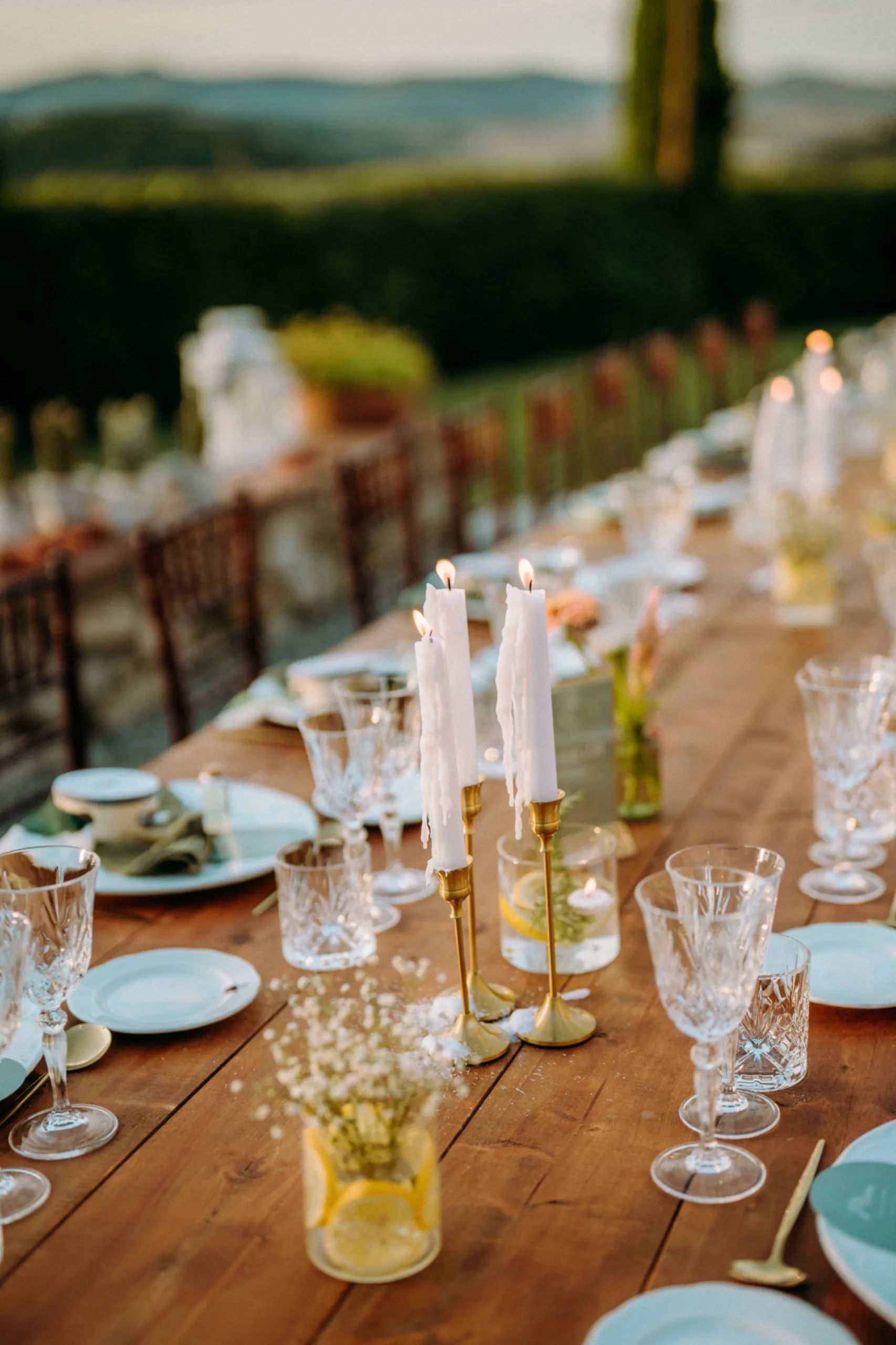 Gedeckte Hochzeitstafel mit Kerzen vor Hügellandschaft