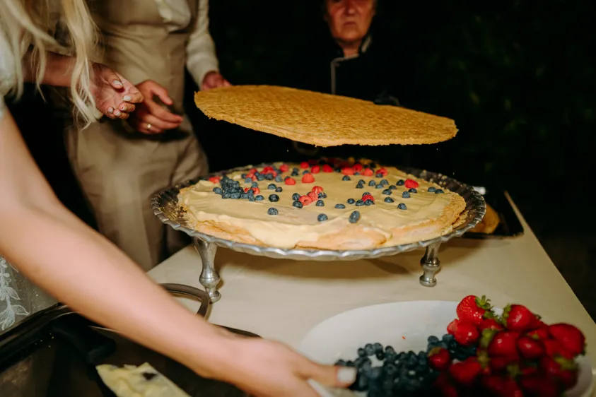 Bride assembling a cream cake with berries in the evening