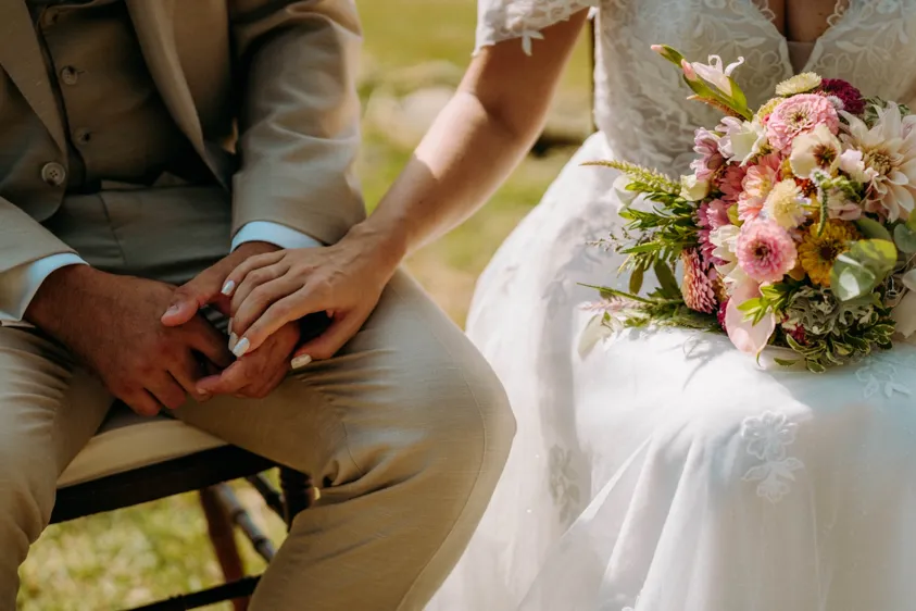 Bride and groom holding hands beside a colourful bouquet
